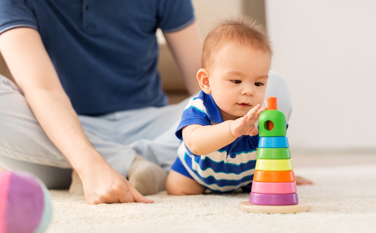 Father Watching Over Toddler Playing with Toys